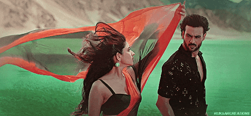 a man and a woman are standing next to each other and the woman is holding a red cloth in her hand