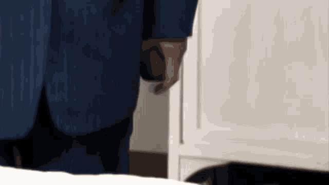 a man in a blue suit is standing in front of a white dresser