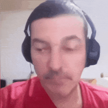 a man wearing headphones and a red shirt with his eyes closed