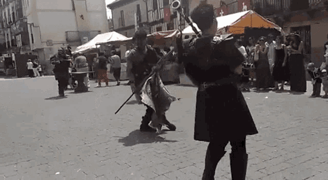 a man in a black coat is playing a bagpipe in a crowded street