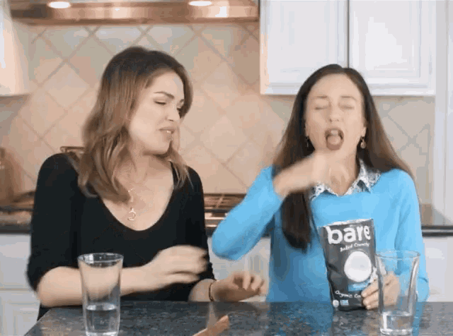 two women are playing with a bag of bare baked crackers