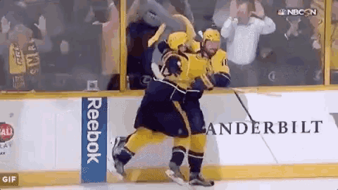 a hockey player is hugging another hockey player on the ice