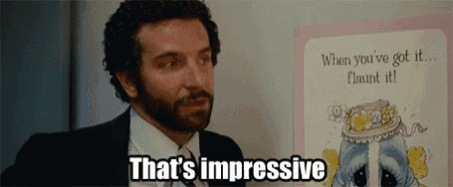 a man in a suit says that 's impressive in front of a picture of a cake