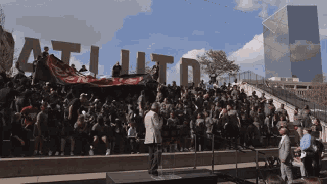 a large crowd gathered in front of a sign that says atl ltd