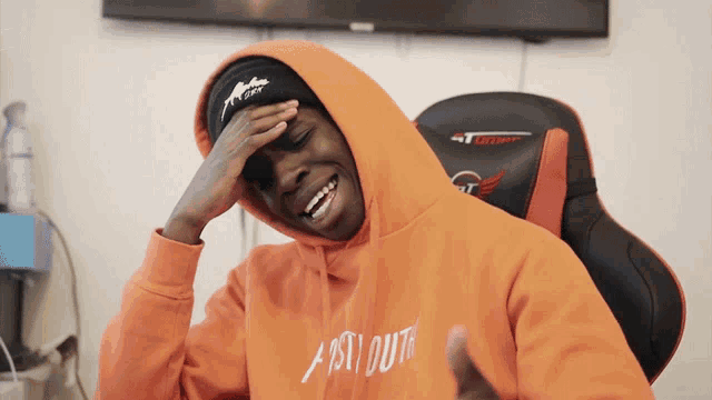 a person wearing an orange hoodie that says ast out
