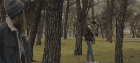 a person walking through a forest with trees in the foreground