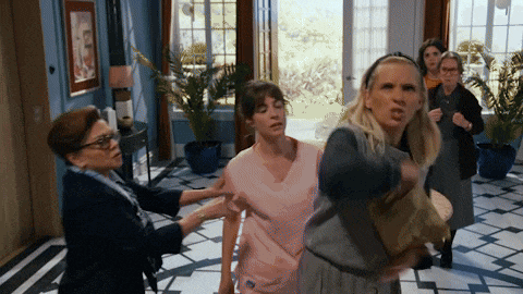 a group of women are standing in a room and one woman is pointing