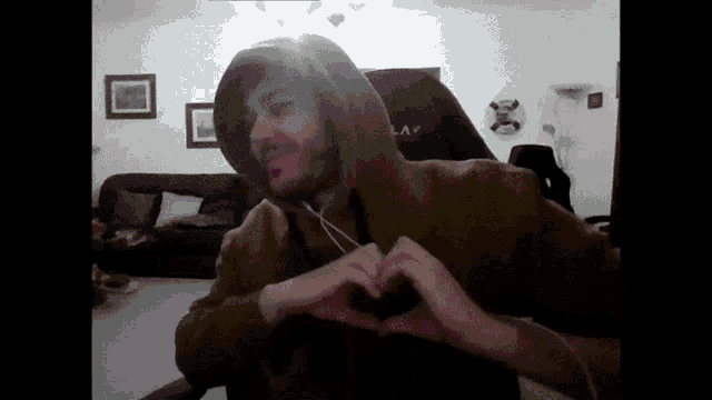 a man wearing a hoodie making a heart shape with his hands