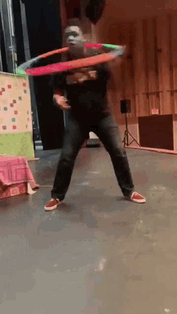 a man in a black shirt is playing with a hula hoop on a stage