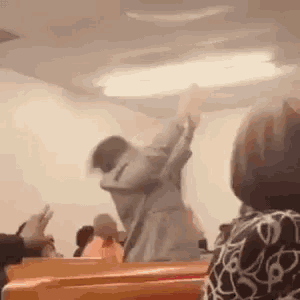 a man is dancing in a church with his arms in the air while a woman watches .
