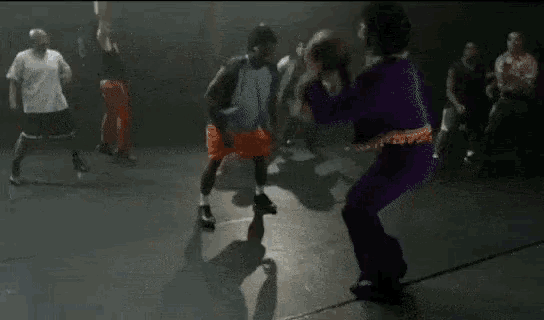 a group of people are dancing in front of a basketball hoop in a dark room