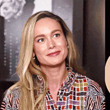 a woman with long blonde hair is wearing a colorful shirt with a striped pattern