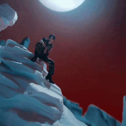a person sitting on a snowy hill with a full moon behind them