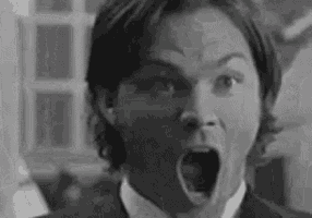 a black and white photo of a man in a suit and tie with his mouth open .