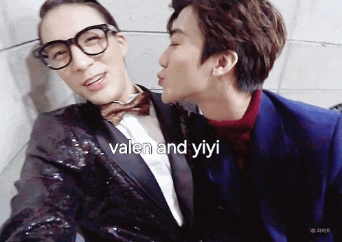 a man in a suit kisses another man on the cheek with the words " valen and yiyi " written on the bottom