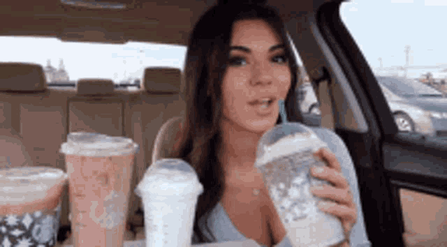 a woman is sitting in a car holding a cup of coffee