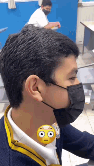 a boy wearing a black face mask with a smiley face on his neck