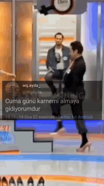 a woman in high heels stands in front of a man in a suit on a stage with a twitter for android notification