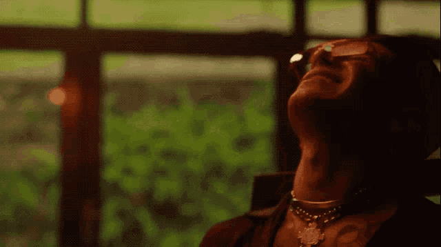 a man wearing glasses and a necklace looks up