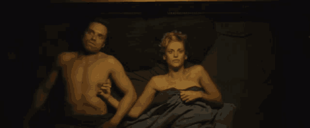 a man and a woman are laying on a bed holding hands