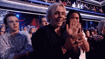 a group of people are sitting in a stadium applauding and clapping .