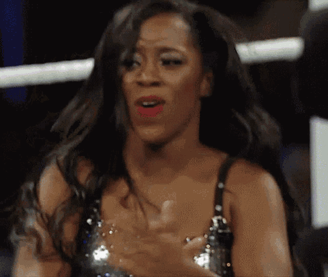 a woman in a sequined top is clapping her hands in a wrestling ring