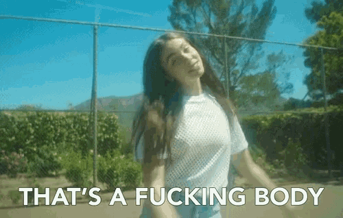a woman is standing in front of a fence with the words that 's a fucking body written below her