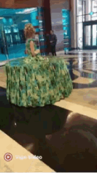 a woman in a green dress is standing in front of a large aquarium