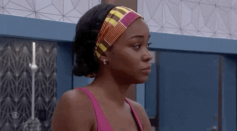 a woman in a pink tank top and a headband is standing in a room .