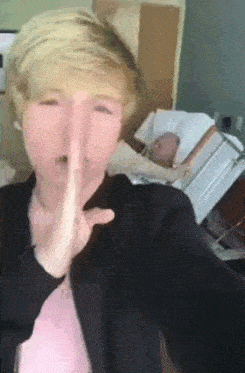 a man is making a shhh gesture in front of a hospital bed