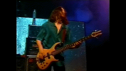 a man in a green shirt is playing a guitar on stage .