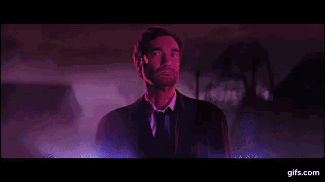 a woman is dancing in a pink room with a purple light behind her .