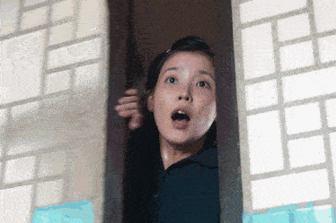 a woman with a surprised look on her face is peeking out of a doorway