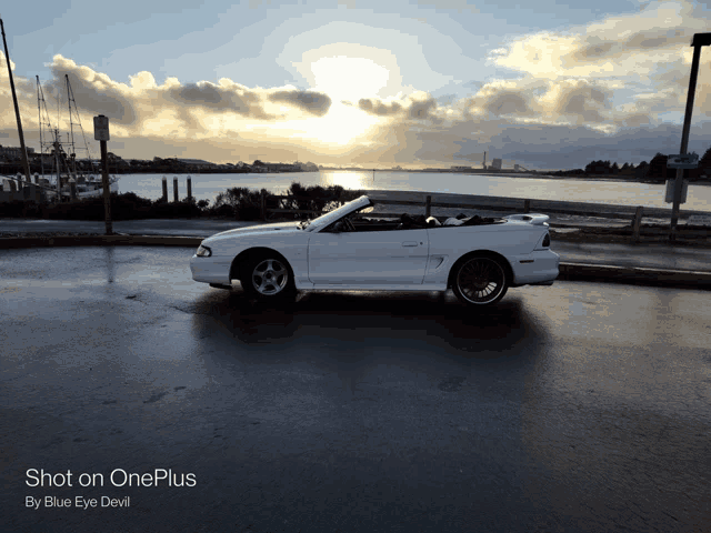 a white convertible mustang is parked on the side of the road with the words shot on oneplus by blue eye devil