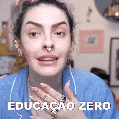a woman wearing a nose ring and a blue shirt has the word educacao zero on her face