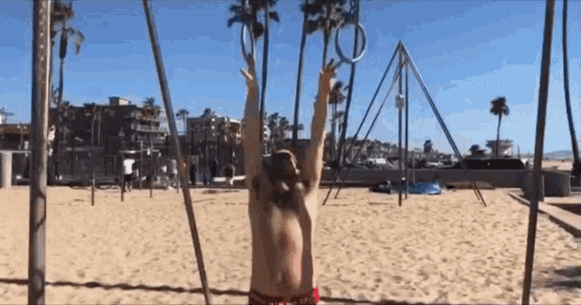 a man is doing exercises on a beach with his arms up