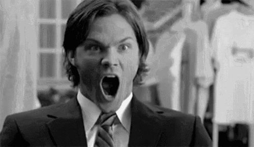 a man in a suit and tie is screaming with his mouth wide open .