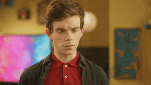 a young man with his eyes closed wearing a red polo shirt and a black jacket