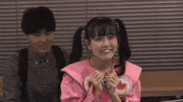 a girl in a pink dress is smiling next to a man in a plaid shirt