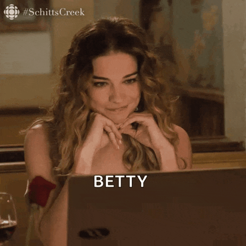a woman is sitting in front of a laptop with the name betty boop on it