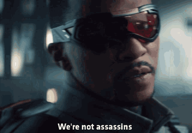 a close up of a man wearing sunglasses with the words we 're not assassins below him
