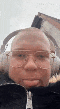 a bald man wearing glasses and headphones is making a funny face .
