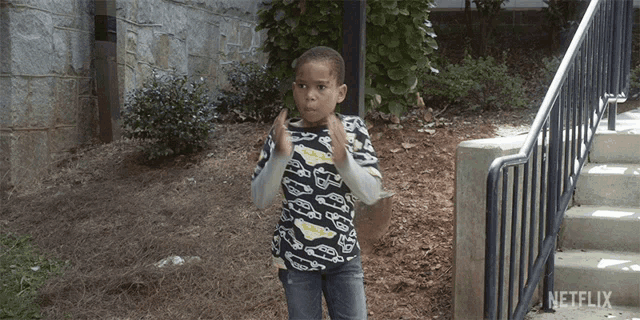 a young boy wearing a shirt with cars on it is standing in front of a netflix sign
