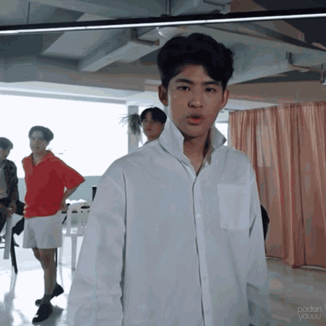 a young man in a white shirt is standing in front of a pink curtain with the words " padan youuu " on the bottom