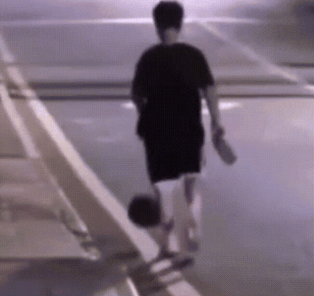 a man in a black shirt is walking down a staircase holding a basketball .
