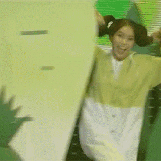 a woman in a yellow and white sweater is jumping in the air with her arms in the air