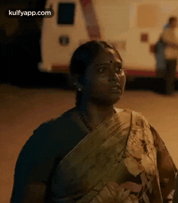 a woman is standing in front of an ambulance at night .