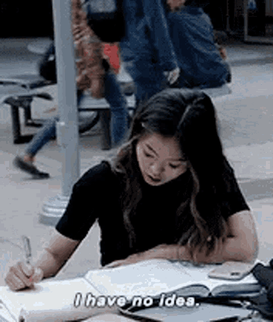 a woman is sitting at a table with a book and a pen .