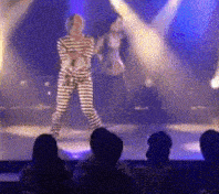 a man in a striped prison uniform sings into a microphone