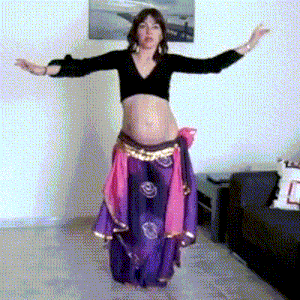 a woman in a black crop top and purple skirt is dancing